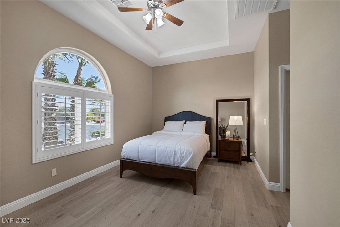 7687 West Pebble Road Las Vegas, NV 89113 - Photo 33 of 79 Bedroom featuring light wood finished floors, visible vents, a tray ceiling, and baseboards