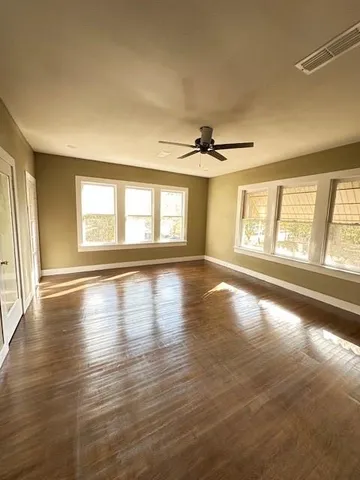 a view of an empty room with a window and wooden floor