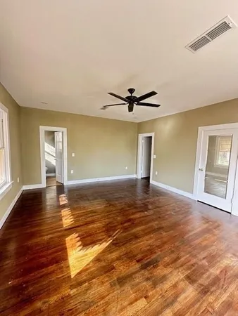 a view of empty room with wooden floor and fan