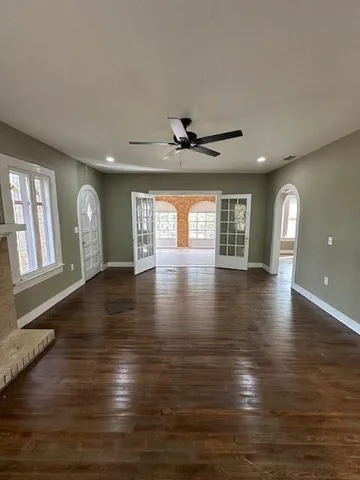 a view of an empty room with window and wooden floor