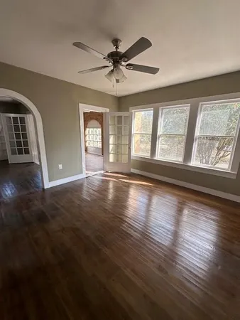 a view of an empty room with wooden floor and a window