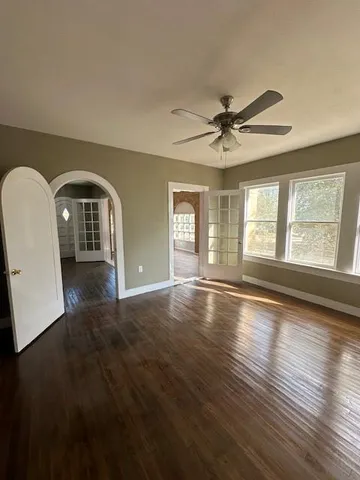 a view of empty room with wooden floor and fan
