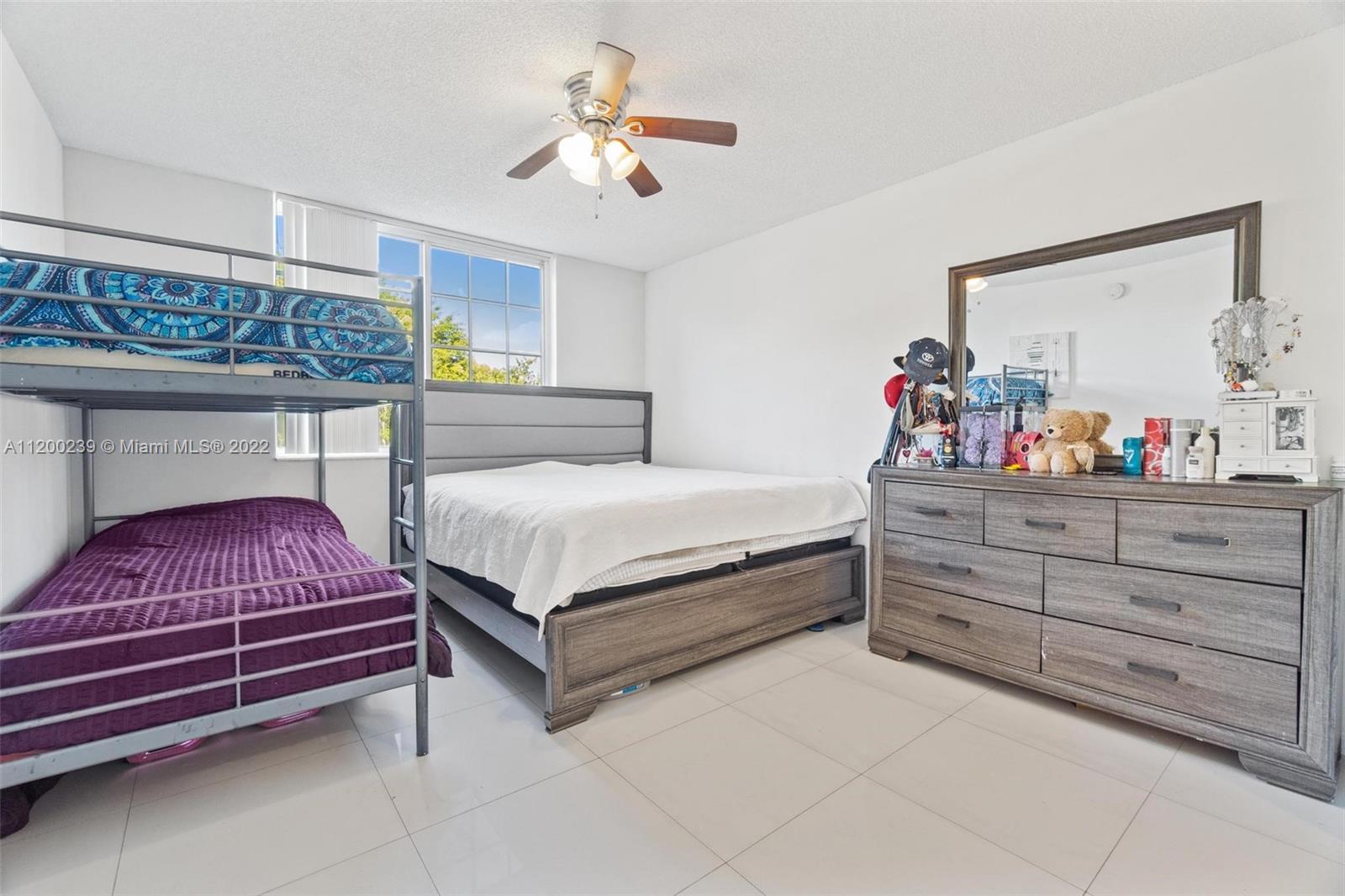 2071 Renaissance Boulevard, Unit 203 Miramar, FL 33025 - Photo 10 of 17 a bedroom with a bed and a chandelier