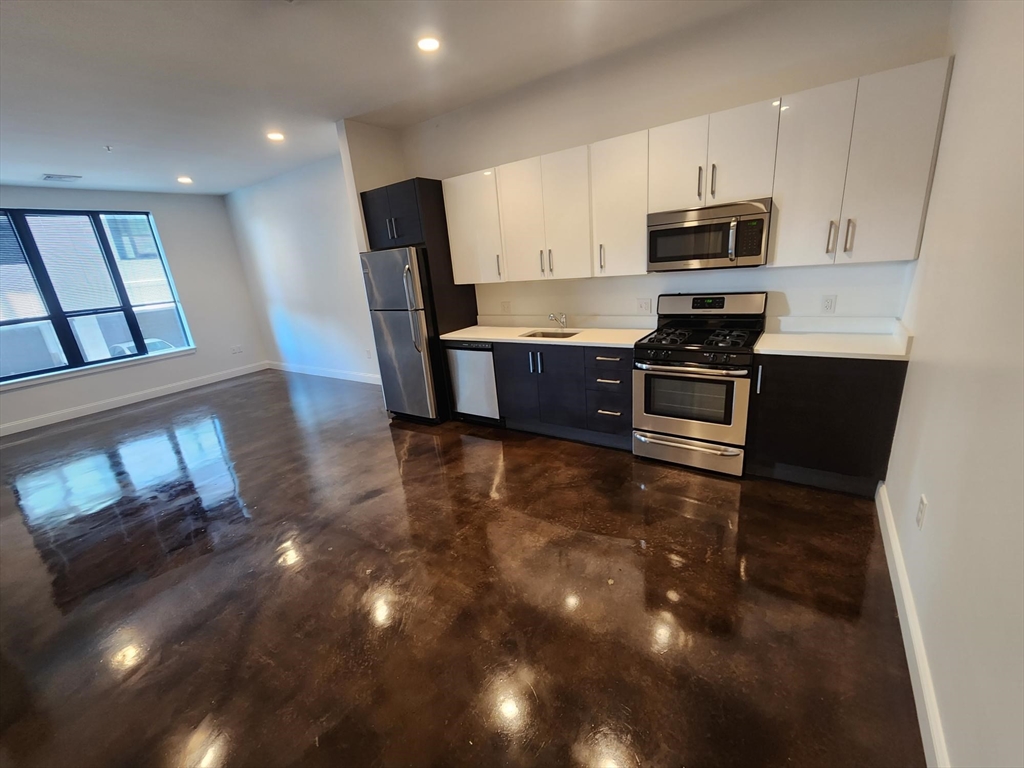 22 Mechanic Street, Unit 507 Quincy, MA 02169 - Photo 1 of 21 a kitchen with granite countertop a stove top oven a sink a dining table and chairs with wooden floor