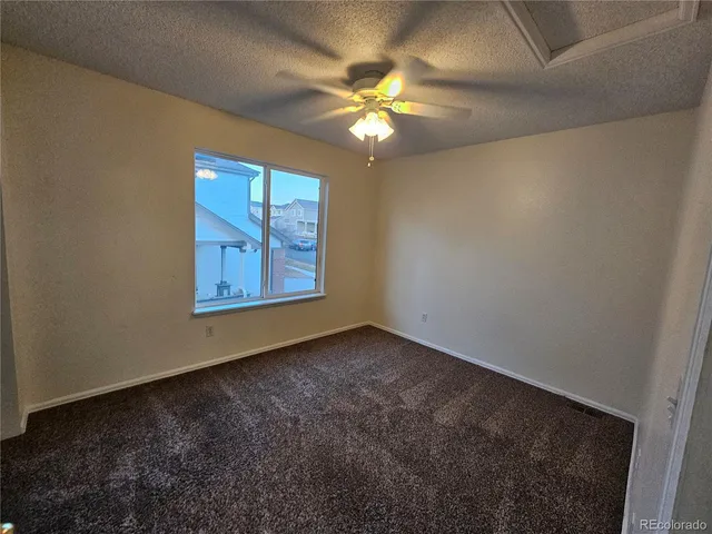 a view of an empty room with window and chandelier fan
