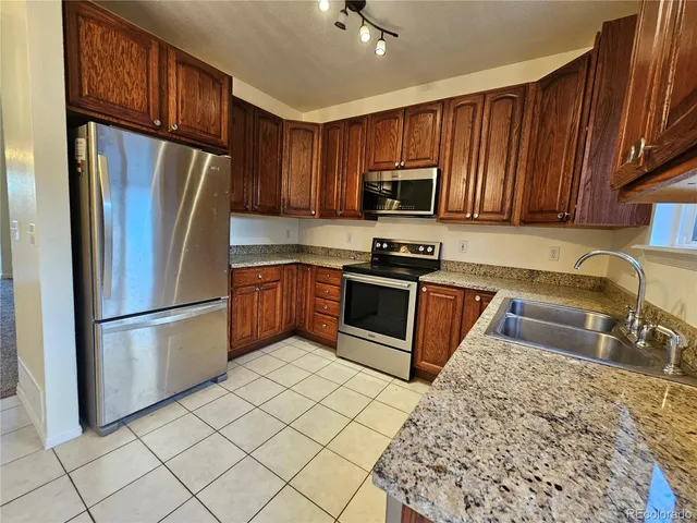 a kitchen with stainless steel appliances granite countertop a refrigerator stove microwave and sink