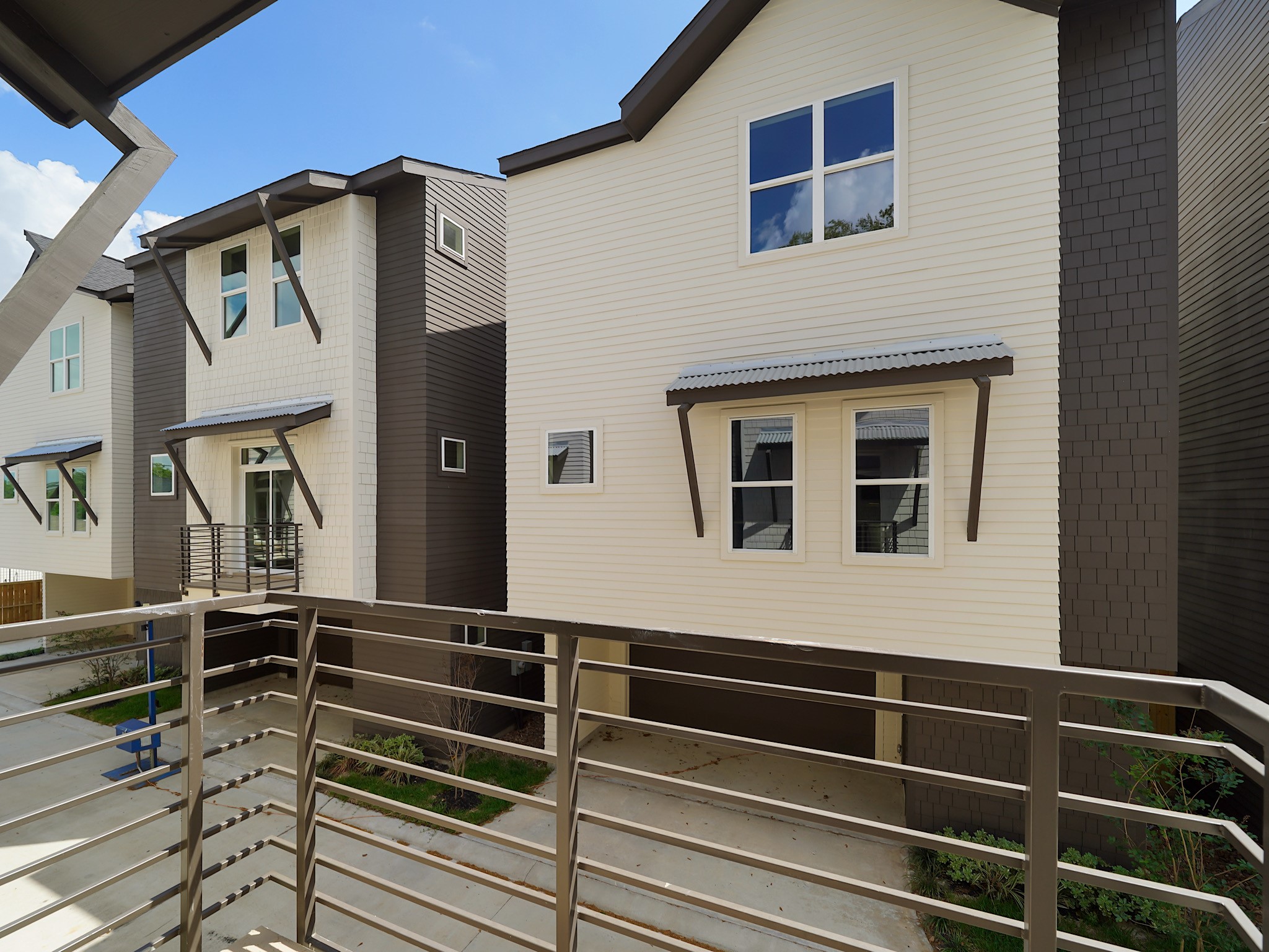 861 Rachel Street, Unit E Houston, TX 77091 - Photo 26 of 29 Modern townhouses with sleek, two-toned exteriors and large windows. The view includes a shared driveway and minimal landscaping, providing a clean and contemporary look.