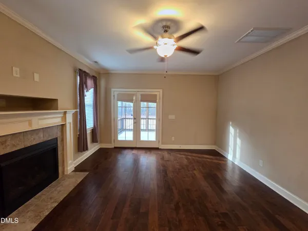 a view of an empty room with wooden floor fireplace and a window