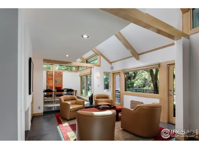 a living room with furniture a large window and wooden floor