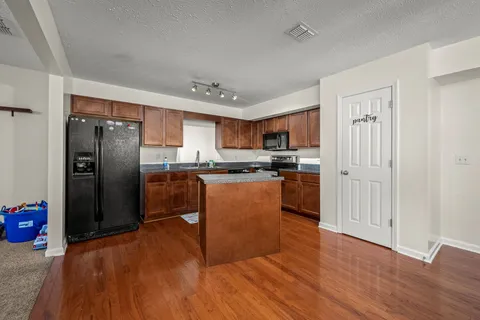 a kitchen with granite countertop stainless steel appliances a refrigerator a stove top oven and a center island