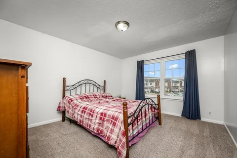 a bedroom with a bed lamp and a large window