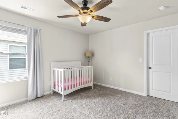 a view of an empty room with window and chandelier fan