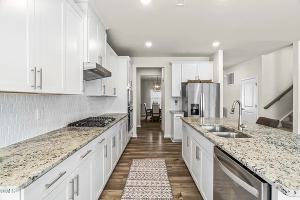 a large kitchen with stainless steel appliances granite countertop a lot of counter space and wooden floor