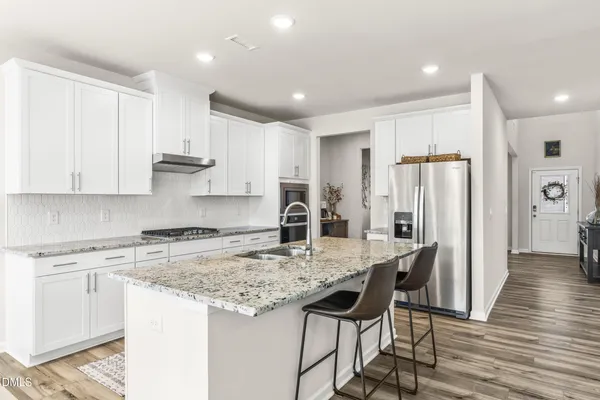 a kitchen with kitchen island granite countertop a sink cabinets and wooden floor