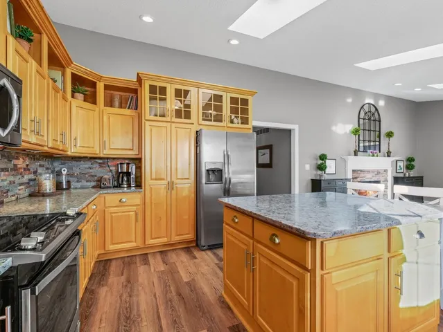 a large kitchen with granite countertop a sink large window white cabinets and stainless steel appliances