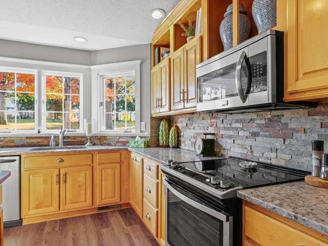 a kitchen with stainless steel appliances granite countertop a sink counter space and wooden floor