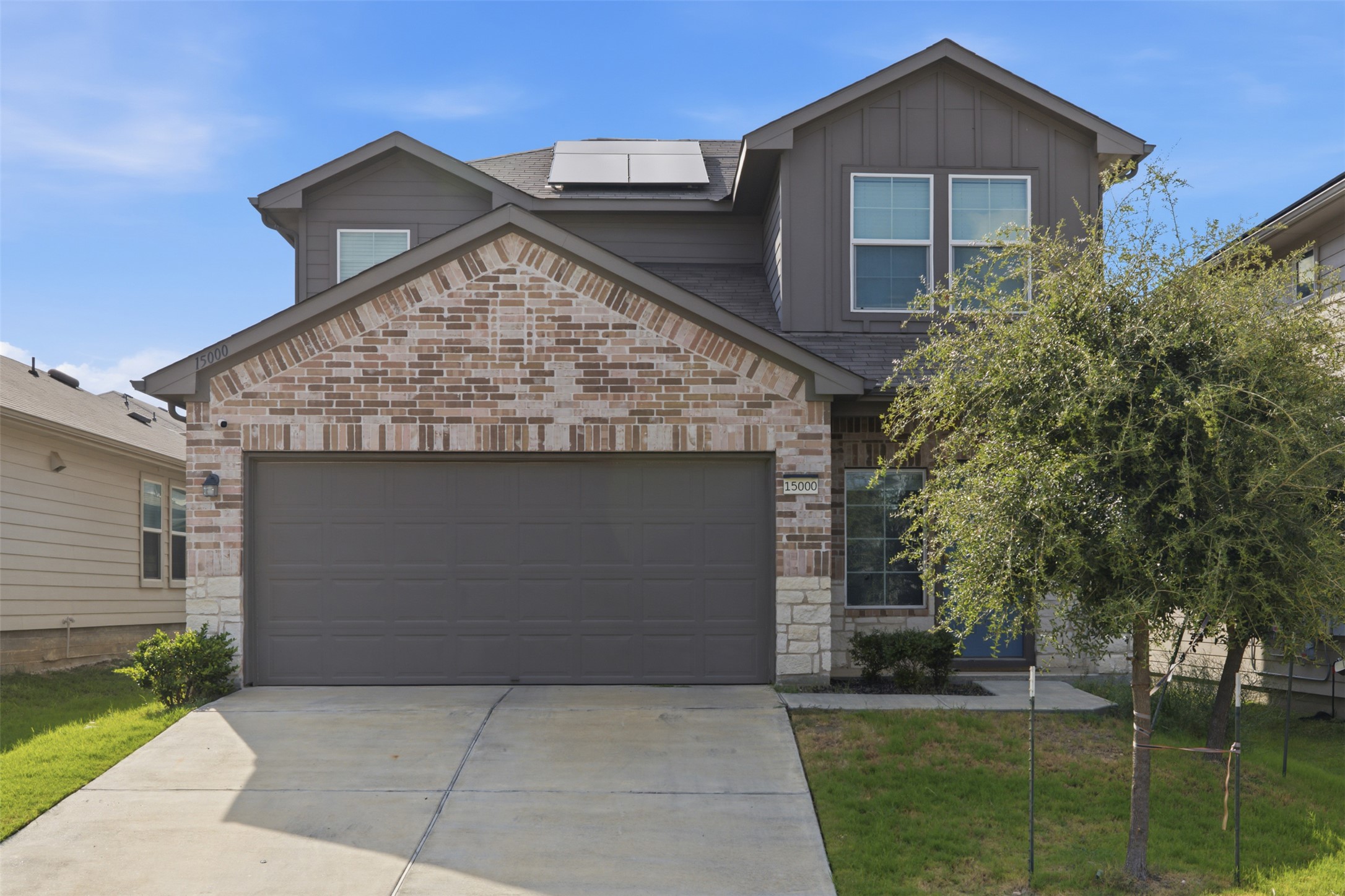 15000 Bajada Rd Manor Manor, TX 78653 - Photo 30 of 31 A welcoming facade with a blend of brick and stone, showcasing modern residential charm and practical solar panels.