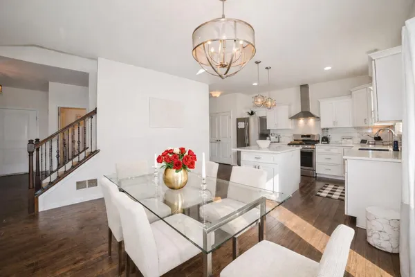 a kitchen with stainless steel appliances kitchen island granite countertop a white cabinets and couches with wooden floor