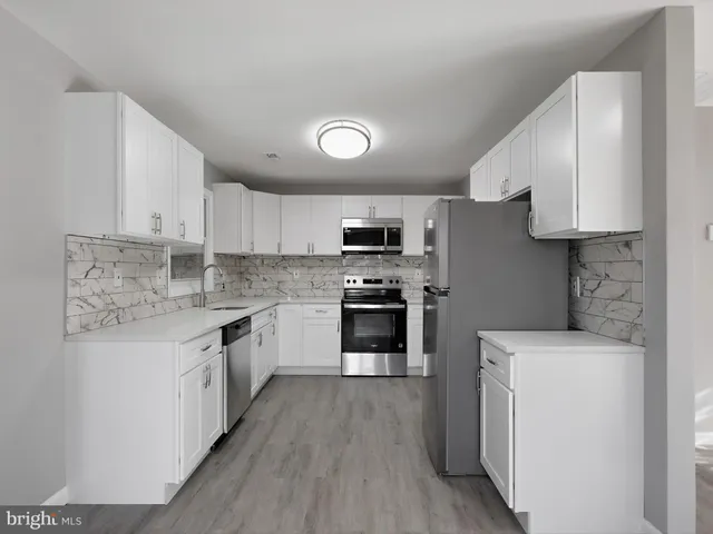 a kitchen with granite countertop a sink a counter top space stainless steel appliances and cabinets