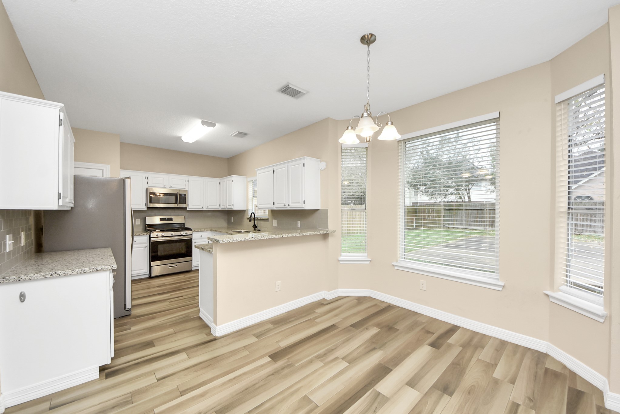 1702 Park Ridge Drive Katy, TX 77450 - Photo 7 of 30 a kitchen with stainless steel appliances granite countertop a sink dishwasher a refrigerator white cabinets and wooden floor next to a window