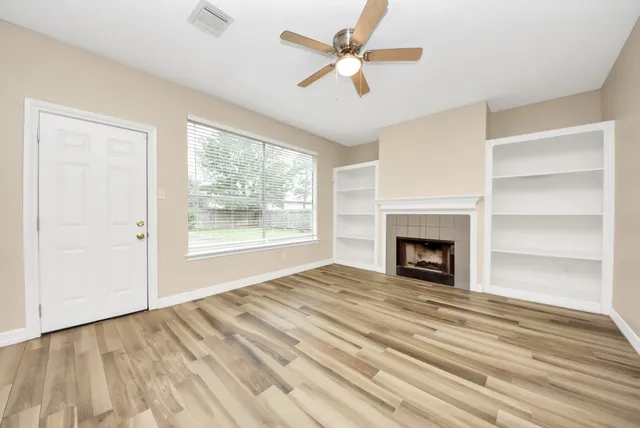 a kitchen with stainless steel appliances granite countertop a sink dishwasher a refrigerator white cabinets and wooden floor next to a window