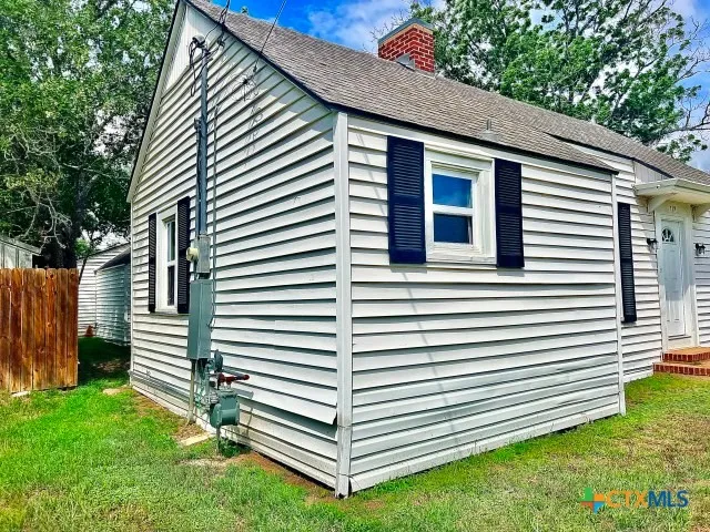 a view of a house with a yard and a large tree