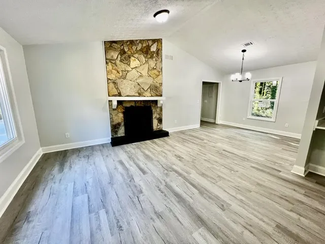 a view of an empty room with a window and wooden floor