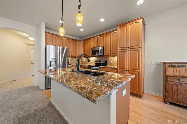 a kitchen with stainless steel appliances granite countertop a refrigerator and a stove top oven