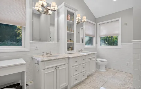a bathroom with a double vanity sink mirror and toilet