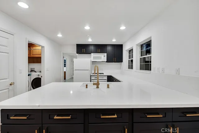 a living room with stainless steel appliances kitchen island a sink a stove and a refrigerator with wooden floor