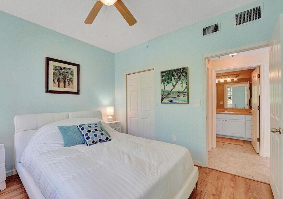9857 Baywinds Boulevard, Unit 9302 West Palm Beach, FL 33411 - Photo 22 of 45 a bedroom with a large bed and a chandelier