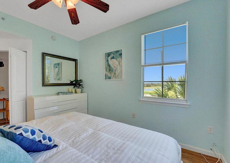 9857 Baywinds Boulevard, Unit 9302 West Palm Beach, FL 33411 - Photo 30 of 45 a bedroom with a bed and a chandelier