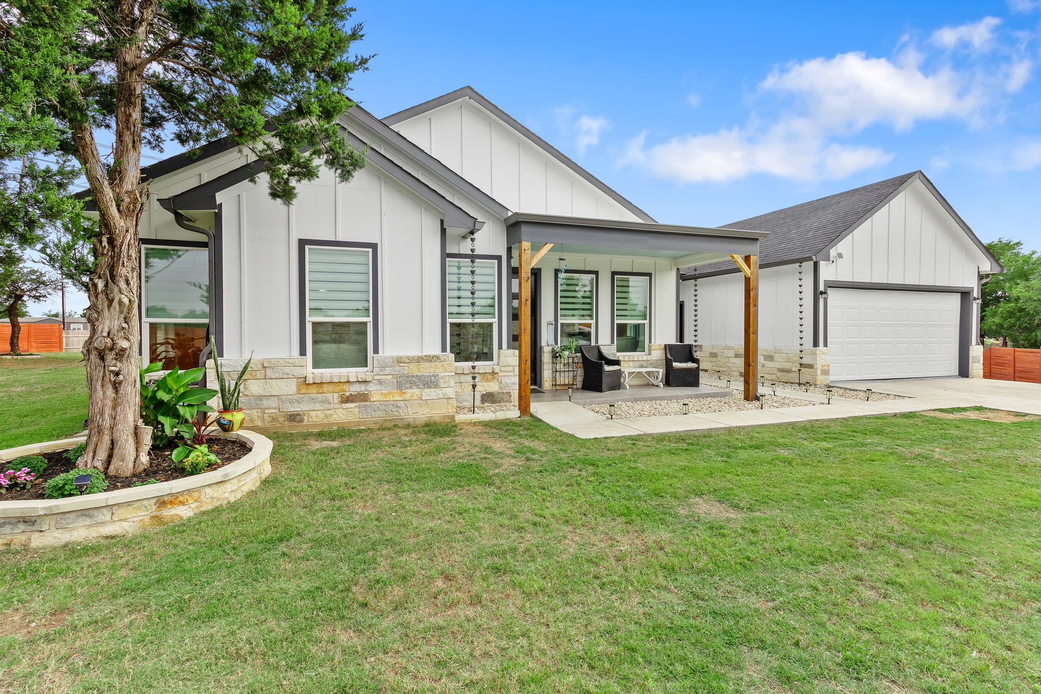 123 Zacate Street Elgin, TX 78621 - Photo 31 of 33 Modern farmhouse exterior featuring board and batten siding, dark trim windows, and a stone accent foundation