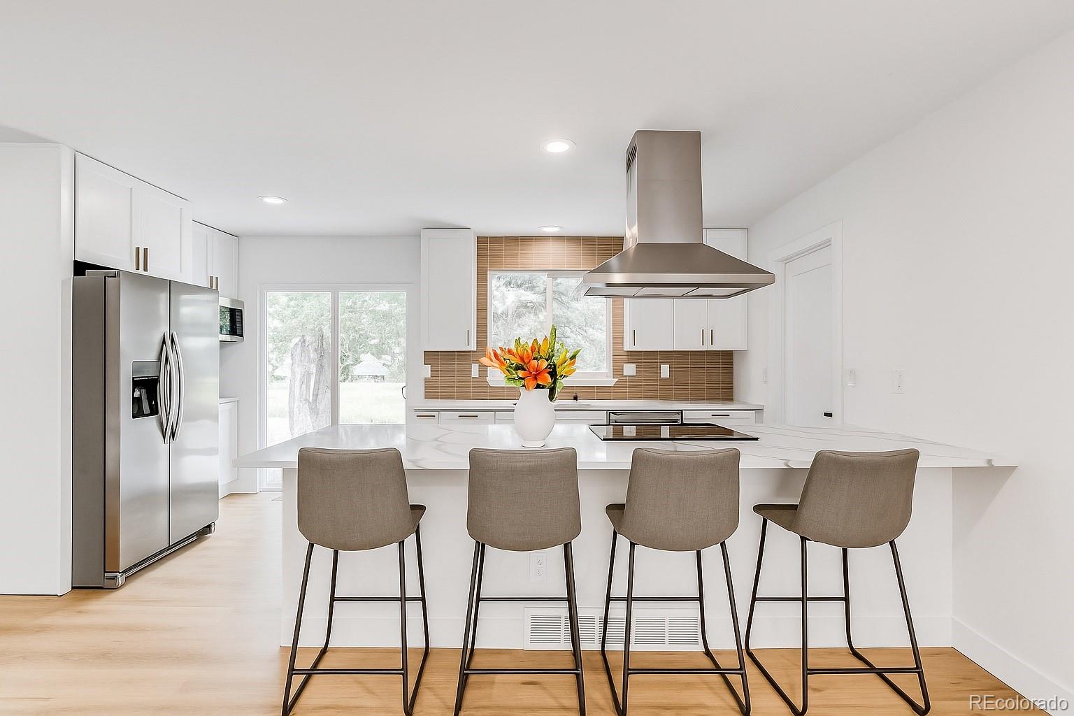 9260 Cody Lane Westminster, CO 80021 - Photo 4 of 18 a kitchen with stainless steel appliances kitchen island granite countertop a dining table chairs and a refrigerator