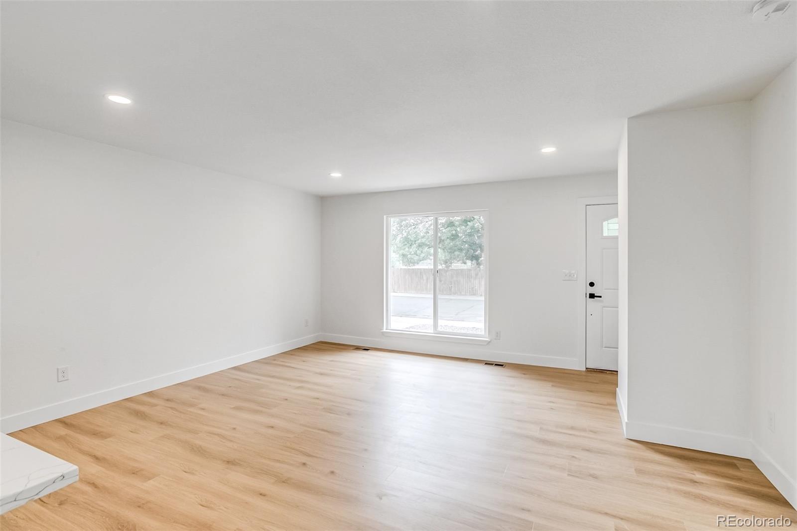 9260 Cody Lane Westminster, CO 80021 - Photo 8 of 18 an empty room with wooden floor and windows