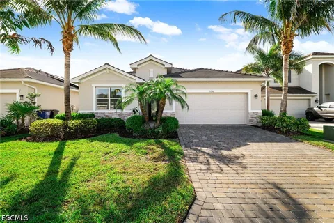 a front view of a house with a garden and palm trees