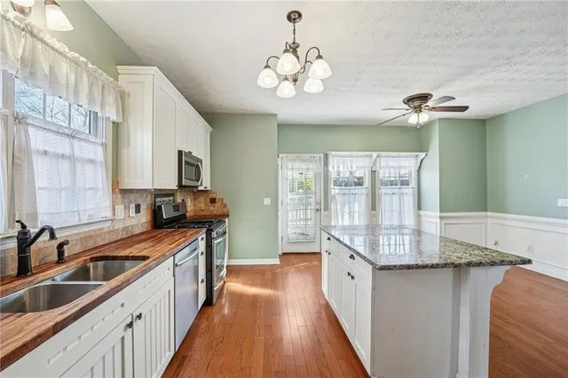 a large kitchen with stainless steel appliances granite countertop a stove top oven a sink dishwasher a dining table and chairs with wooden floor