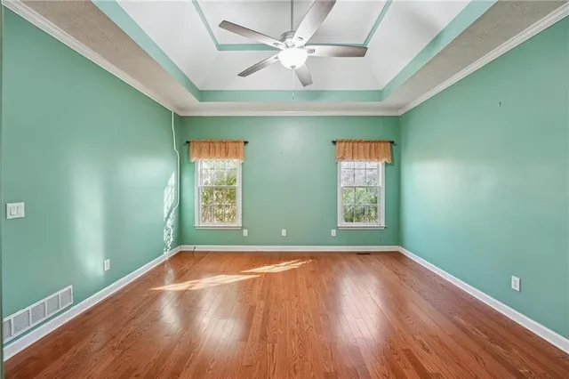 an empty room with wooden floor fan and windows