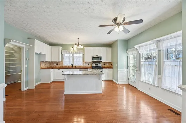a large kitchen with cabinets wooden floor and stainless steel appliances