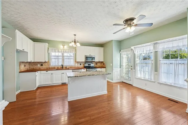 a kitchen with kitchen island granite countertop a sink appliances cabinets and a counter top space