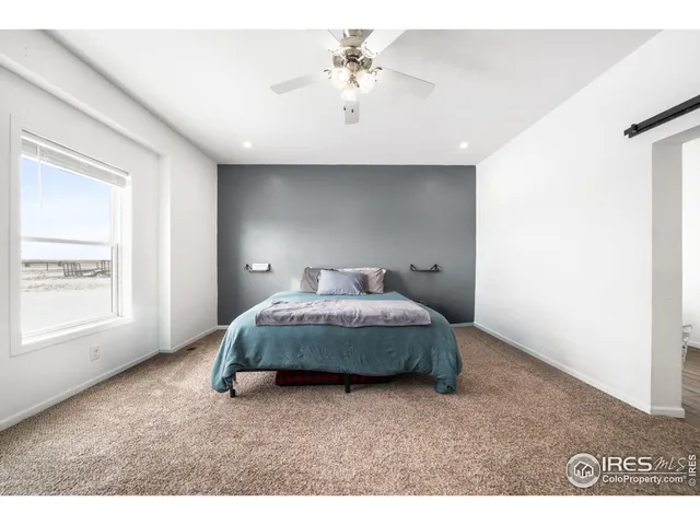 a spacious bedroom with a bed and a flat screen tv