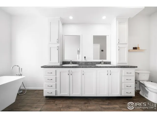 a bathroom with a granite countertop double vanity sink a mirror and a bathtub
