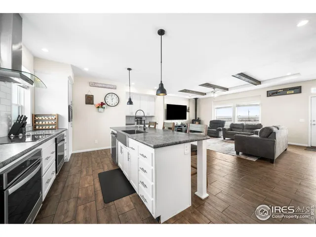 a kitchen with stainless steel appliances kitchen island granite countertop a stove a sink and a refrigerator with wooden floor