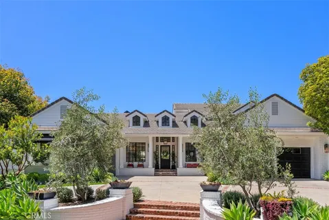 a view of a white house with a big yard and potted plants