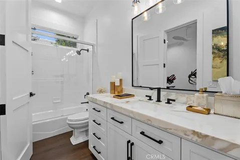 a bathroom with a granite countertop tub sink toilet and mirror