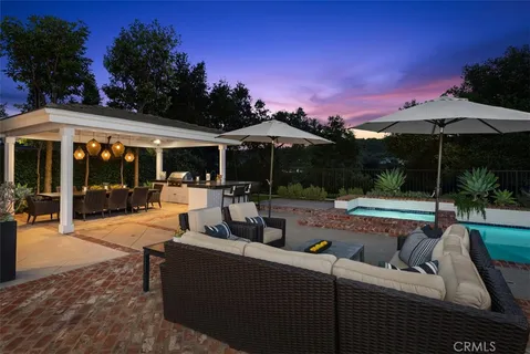 a view of a patio with couches and table and chairs under an umbrella with palm trees