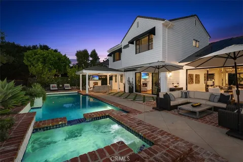 a view of a house with backyard swimming pool and sitting area