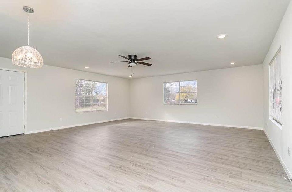 2003 West Bond Street Denison, TX 75020 - Photo 10 of 16 an empty room with wooden floor chandelier fan and windows