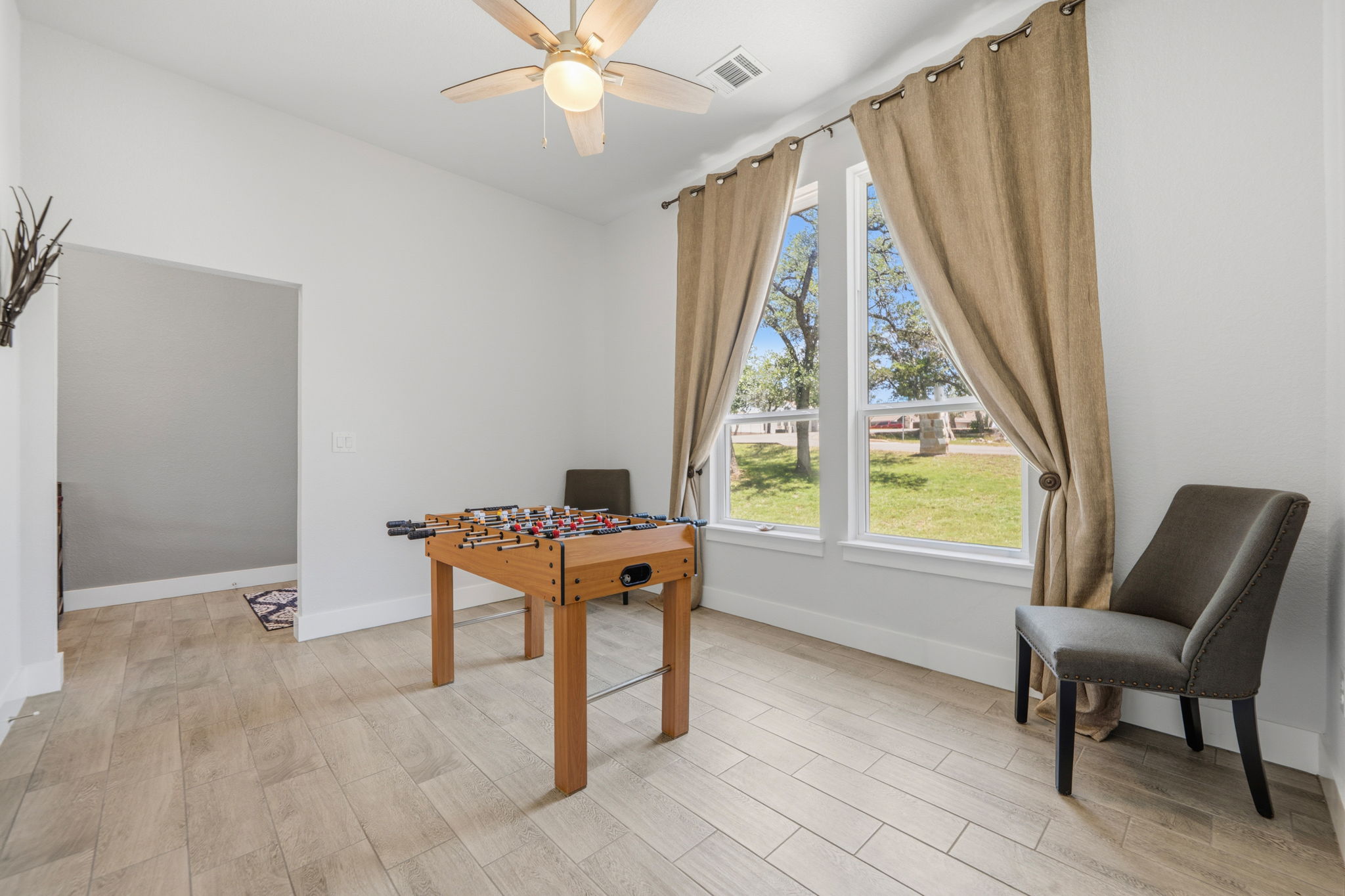 18605 Masters Cove Point Venture, TX 78645 - Photo 3 of 40 Bright room featuring a ceiling fan with integrated lighting, wood-finish flooring, and large windows with exterior landscaping visible