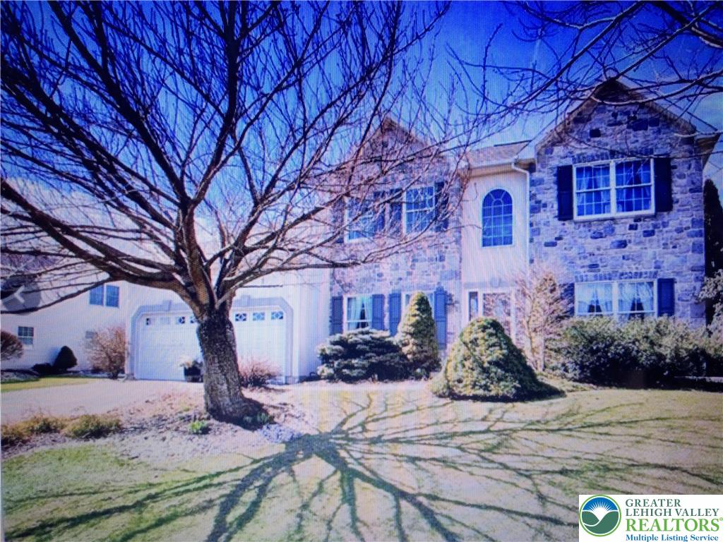 A grand stone facade and arch-top window define this stately residence, framed by mature landscaping. (Winter)